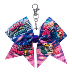 A cheerleader-style keychain bow with a silver clasp, featuring a colorful printed design with racing graphics, the words 'LADIES, START YOUR ENGINES,' and a purple center loop.
