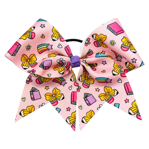 A pink hair bow with a colorful pattern of school supplies, flowers, and stars, attached to a black elastic band with a purple center, shown on a plain white background.