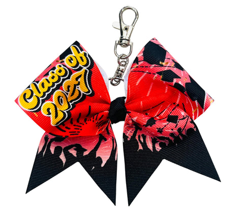 A cheerleader-style keychain bow with a silver clasp, featuring a red and black patterned design with 'Class of 2027' text on one side.