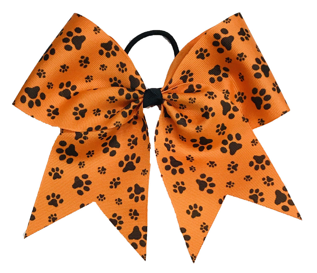 Orange hair bow with black paw prints on a white background