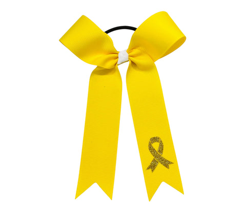 A bright yellow ribbon hair bow for childhood cancer awareness, featuring a glittery yellow awareness ribbon printed on one tail, set against a plain white background.