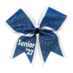 A cheerleader hair bow featuring a columbia blue glitter center with white ribbon borders and white lettering that reads 'Senior '27' on the lower left ribbon, shown on a plain white background.