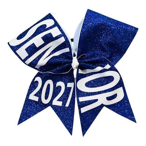 A royal blue glitter cheerleader hair bow with white text reading 'SENIOR 2027' on a plain white background.